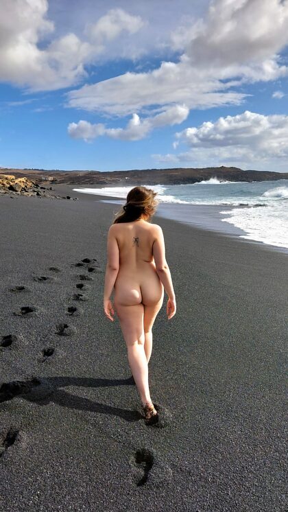Caminhada nua na praia de areia preta