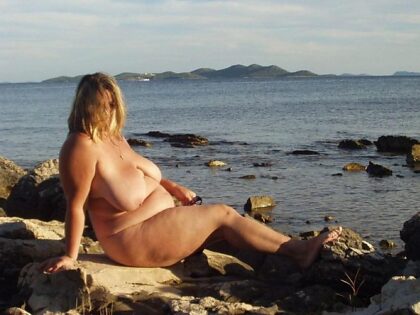 Nude woman sunbathes by tide pool. Source unknown.