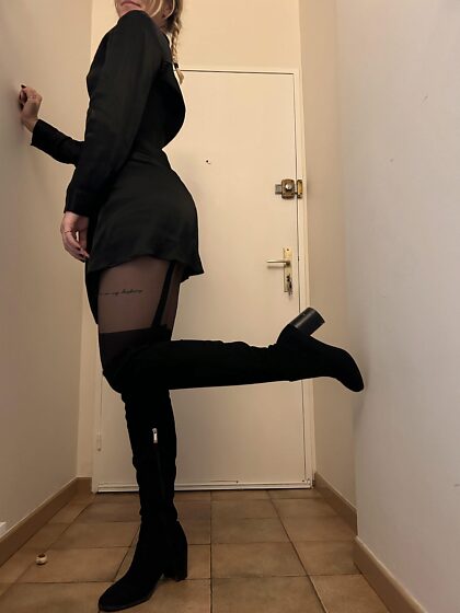 Schwarze Stiefel, schwarze Strümpfe und schwarzes Kleid