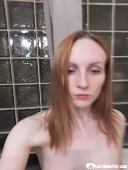Magere roodharige meid poseert naakt in haar badkamer