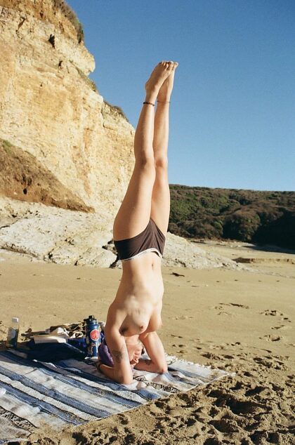 Nudie headstands by the sea